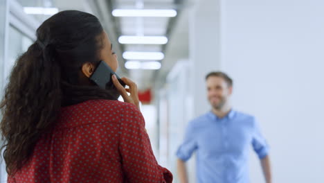 African girl talking mobile phone office. Back view woman smiling colleague