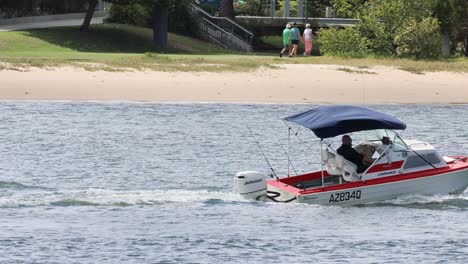 motorboat with passengers cruising by a riverside park