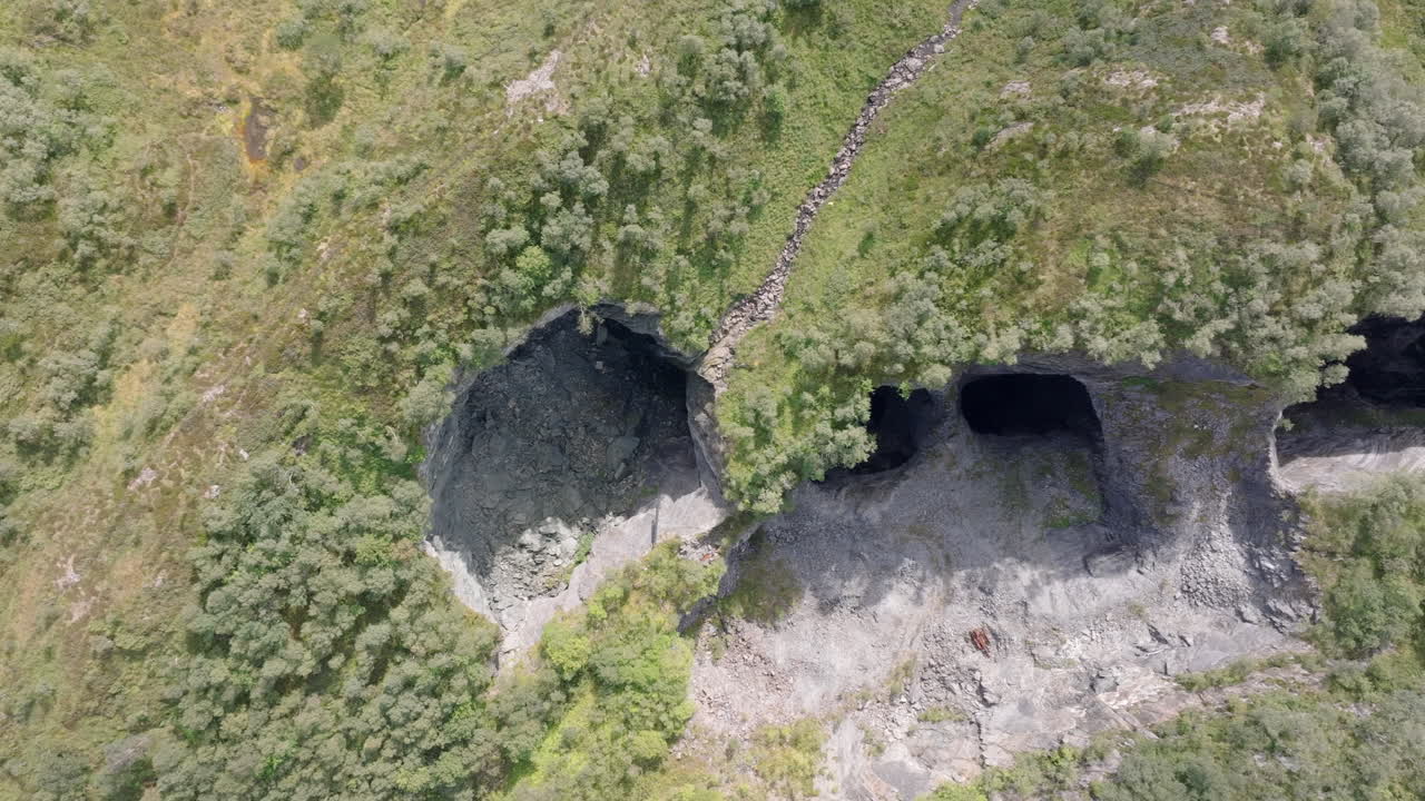 Drone flying above a remote limestone quarry in Norway, showing steep rock walls, mountain scenery, and industrial ruins