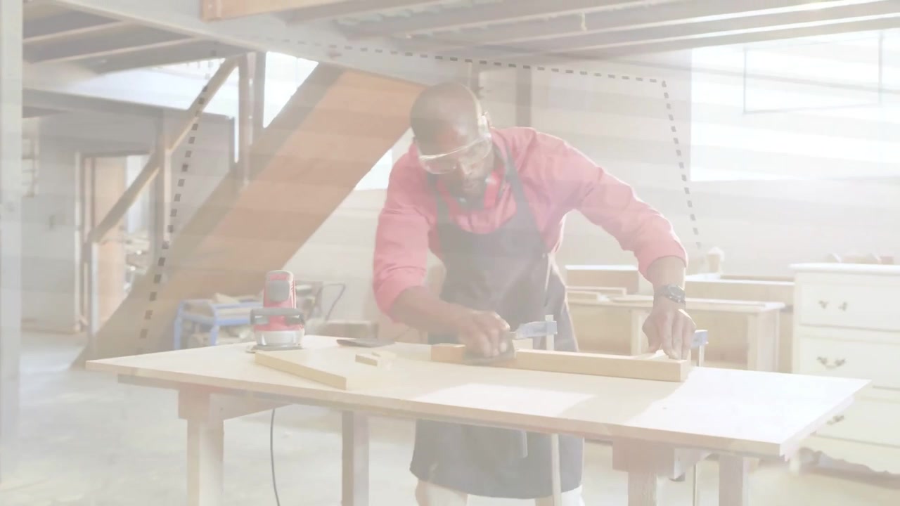 Mature woodworker taking control as helpers stepping back, planing boards, clamping, inspecting fit