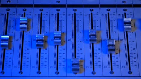 estudio de grabación profesional. interfaz de equipos de sonido para mezclar música. fader. diferentes modos de consola de audio. proceso de trabajo en canción o voz. luz azul neón. 4k