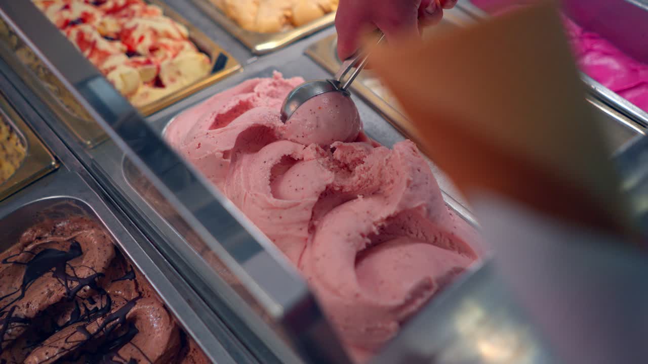 Servire gelato alla fragola rosa in una gelateria italiana