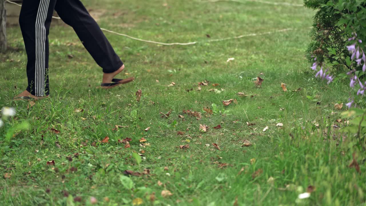 Close-up of mowing the lawn. Female Mowing Lawn in Suburbs.