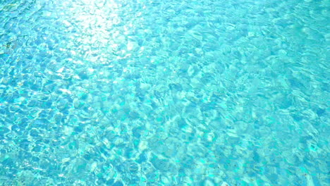 top view of a crystal clear turquoise water of some swimming pool with sun reflecting on its surface