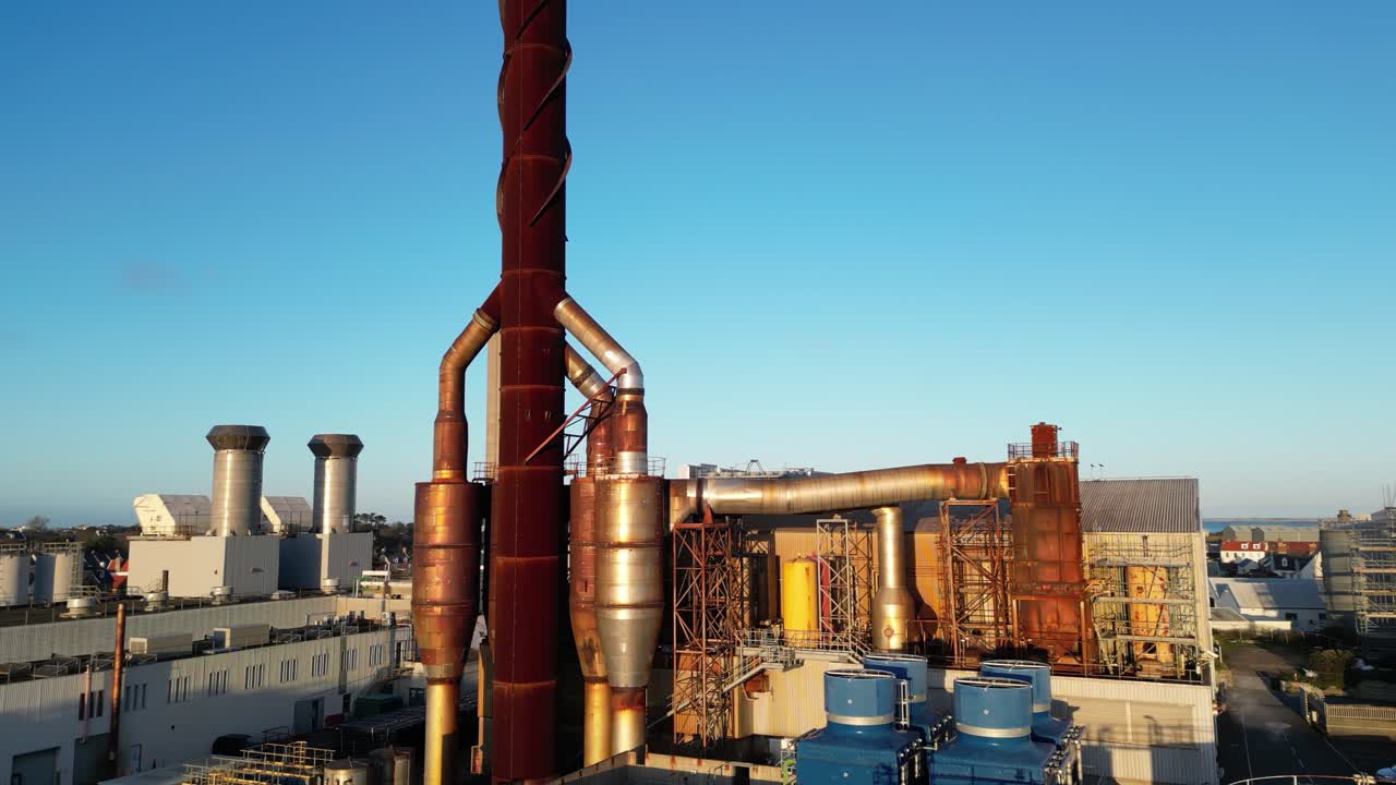 Slow pan of Power Station Guernsey showing chimneys and equipment with golden sun