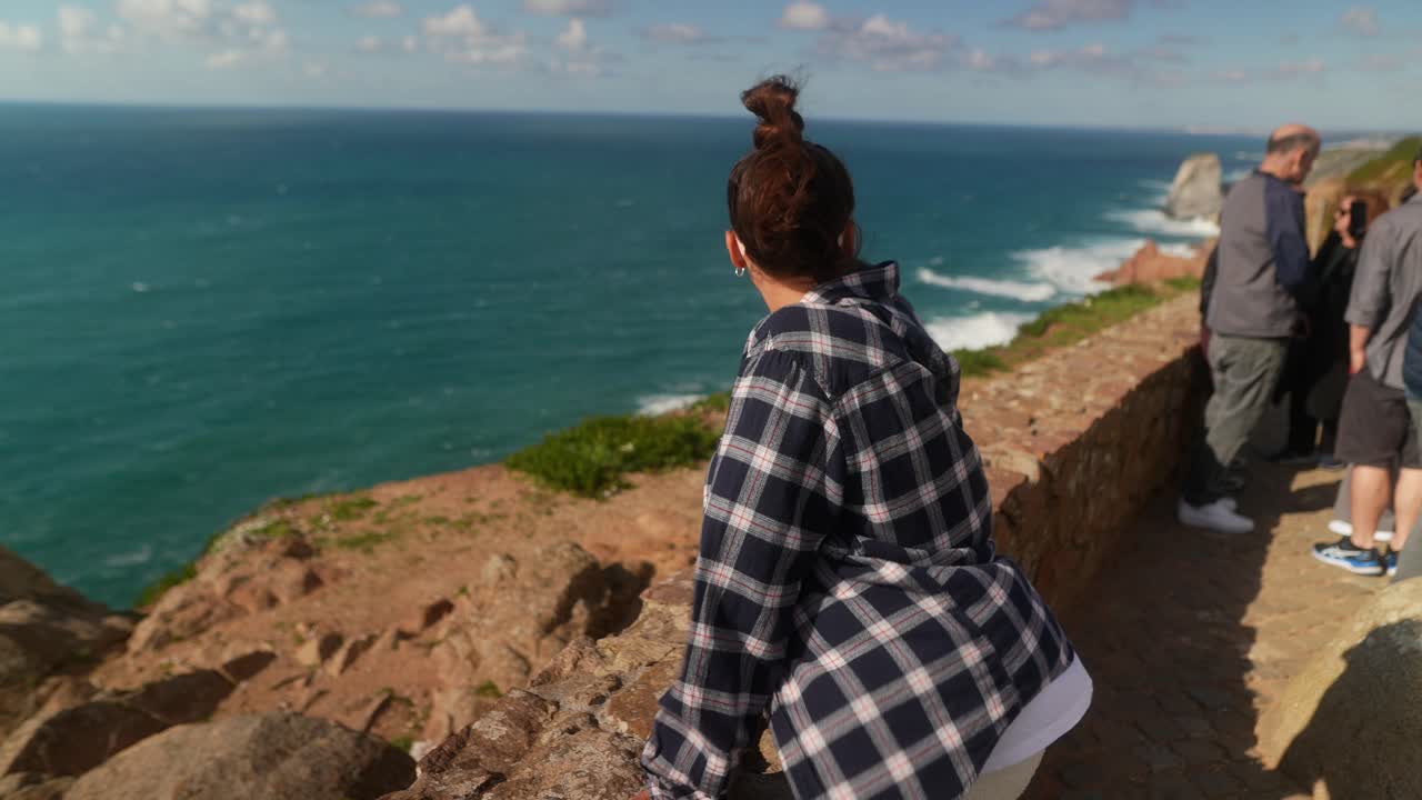 mujer disfrutando de una vista del océano desde un acantilado