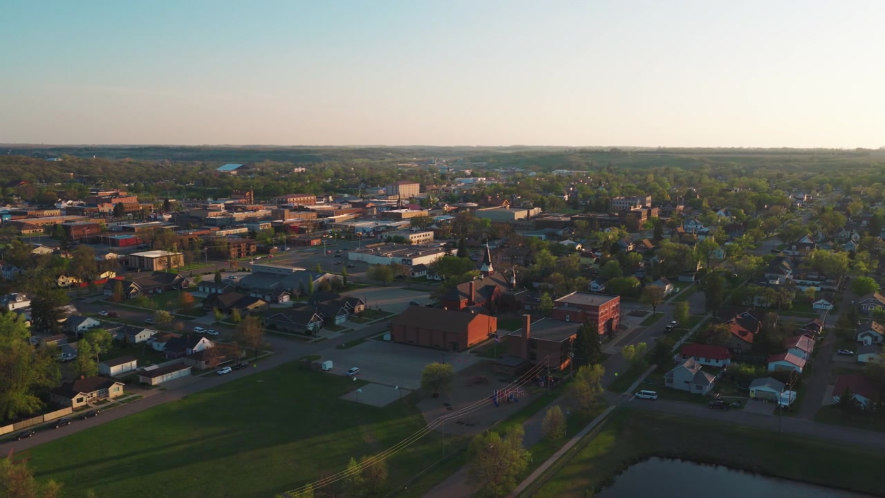 Panorama aereo di una città del Midwest al crepuscolo — campanile di chiesa, edifici in mattoni e strade alberate si estendono fino all'orizzonte, drone di Valley City, Dakota del Nord