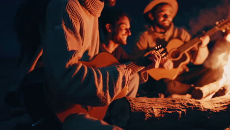 friends playing guitar by a campfire on the beach at night