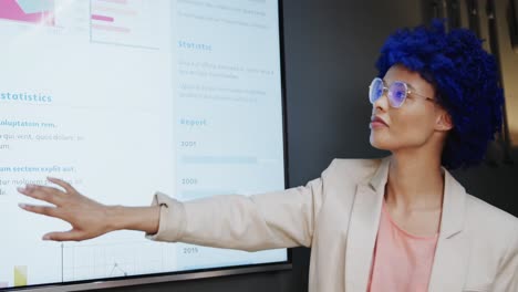 biracial casual businesswoman with blue afro making presentation in office, slow motion