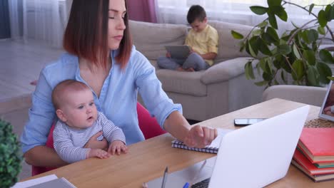 mother with children working on laptop in living room