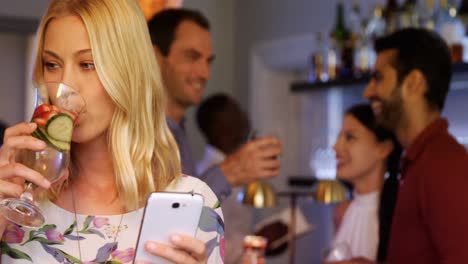 Beautiful-woman-using-mobile-phone-while-having-cocktail