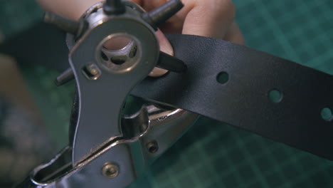 Skilled-worker-makes-holes-in-leather-belt-close-view