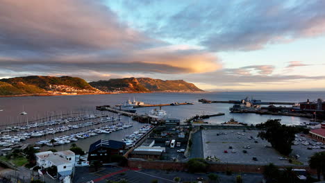 Aerial-cinematic-drone-sunrise-Simon's-Town-naval-boat-marina-fishing-small-quite-city-Cape-Town-South-Africa-early-sunlight-clouds-Table-Mountain-Fish-Hook-Muizenberg-penguins-park-lot-up-movement