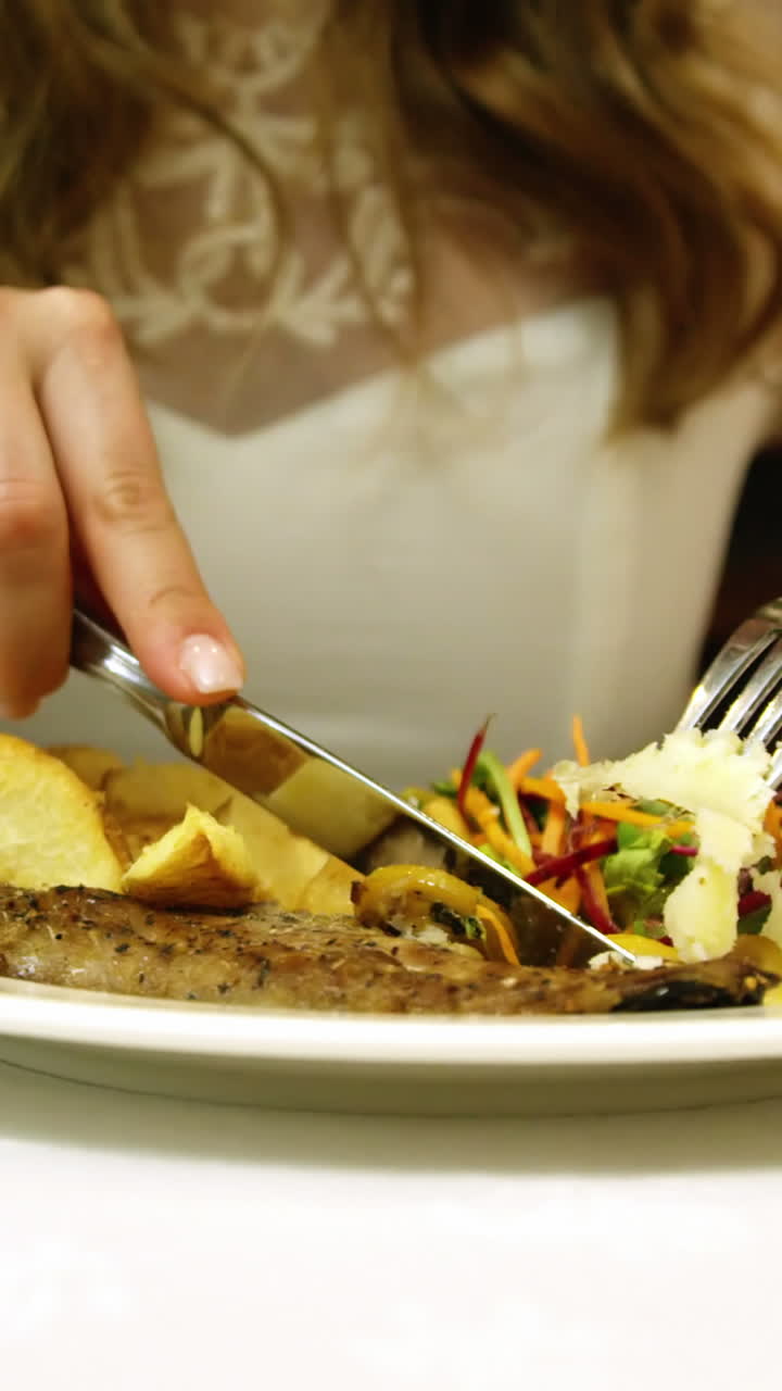 una chica bonita comiendo un plato de pescado en un restaurante