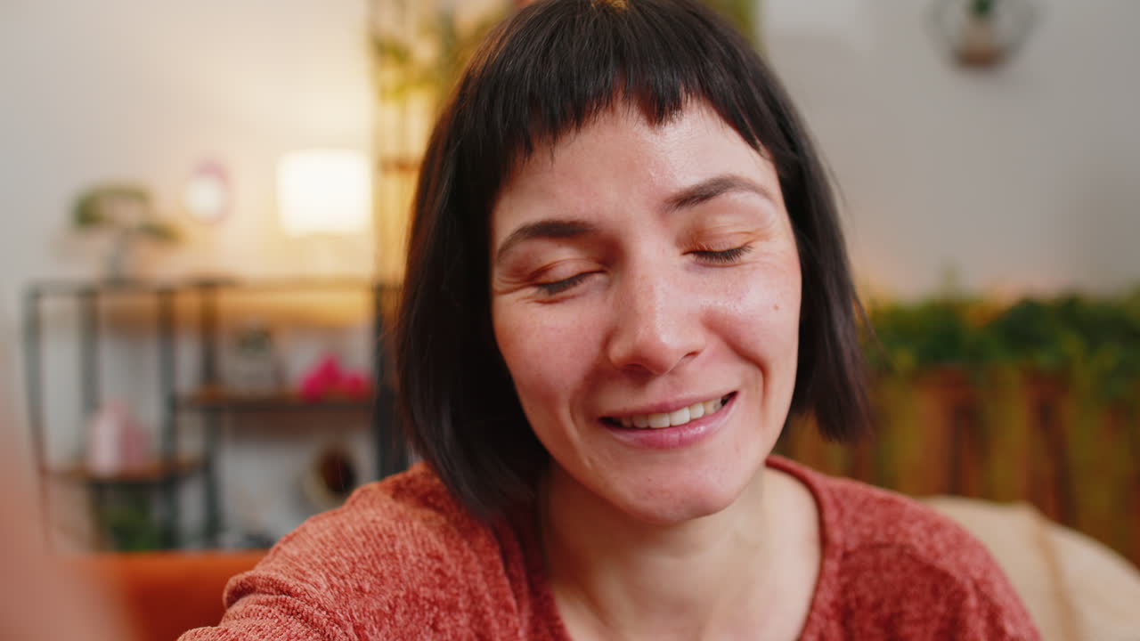POV di una giovane donna che fa una videochiamata online, parla, saluta con la mano guardando la camera e manda un bacio