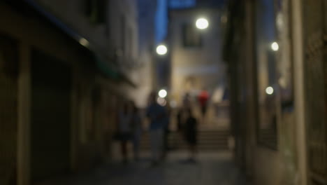 night scene in a european city: people walking through a dark alley