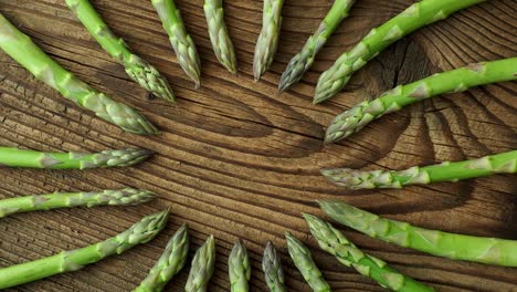 raw garden asparagus stems. fresh green spring vegetables on wooden background. (asparagus officinalis).
