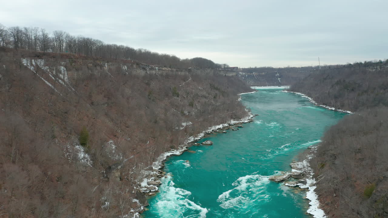 Aerial shot of green blue river flowing quickly through gorge