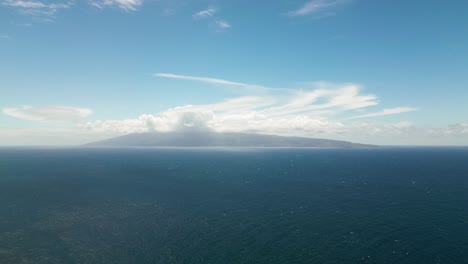 distant island in a vast ocean under a blue sky