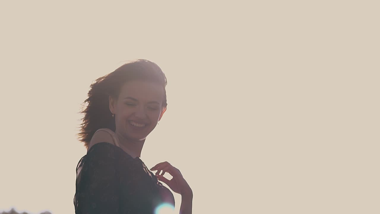 chica positiva en vestido negro posa en el sol en cámara lenta