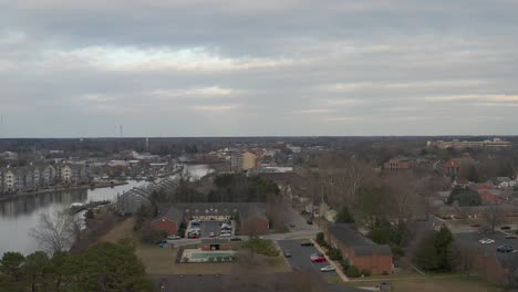 a drone flies over houses and buildings by the side of a river