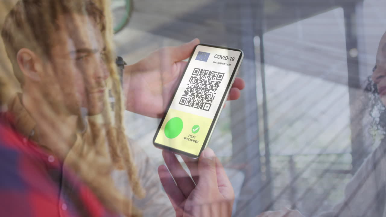 Animation of woman holding smartphone with covid 19 vaccination passport over people in restaurant