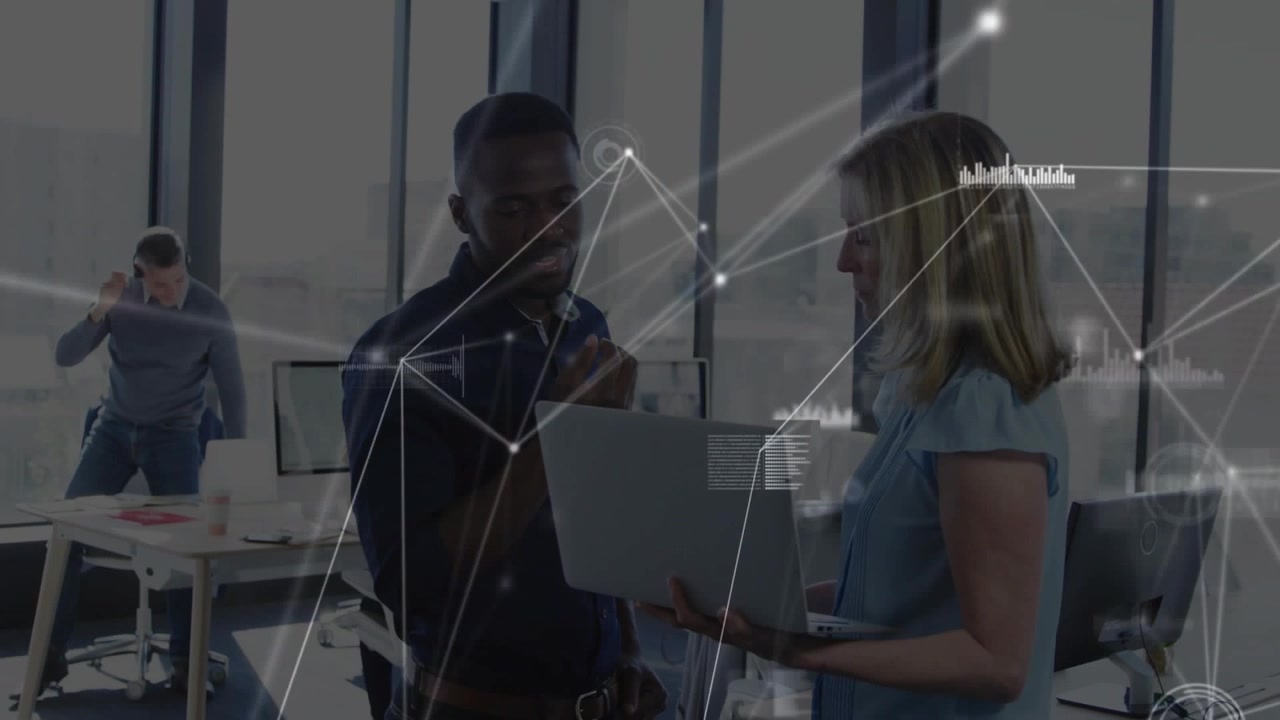 Woman holding laptop toward man while both reviewing tech data, network HUD drifting across screens