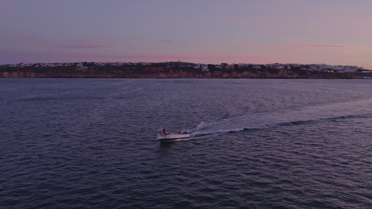 Orbita aerea intorno a un motoscafo che naviga nell'Oceano Atlantico vicino a Praia dos Arrifes all'alba.