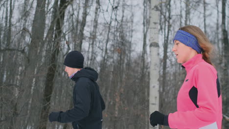 Positives-Schönes-Junges-Gesundes-Paar,-Das-Am-Wintermorgen-Mit-Sportkleidung-Durch-Den-Wald-Läuft