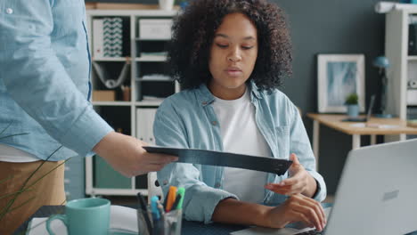 young woman working on a laptop and reviewing documents