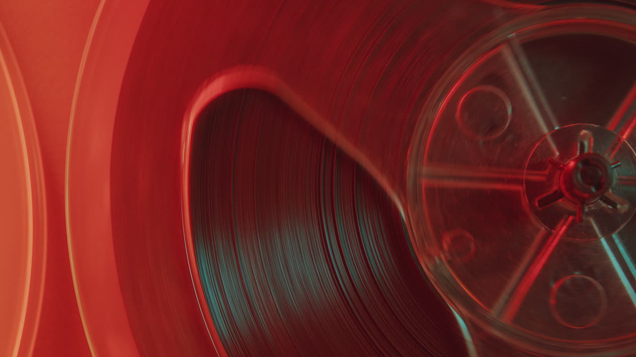 Detailed View of Spinning Reel of Old Tape Recorder in Red Light