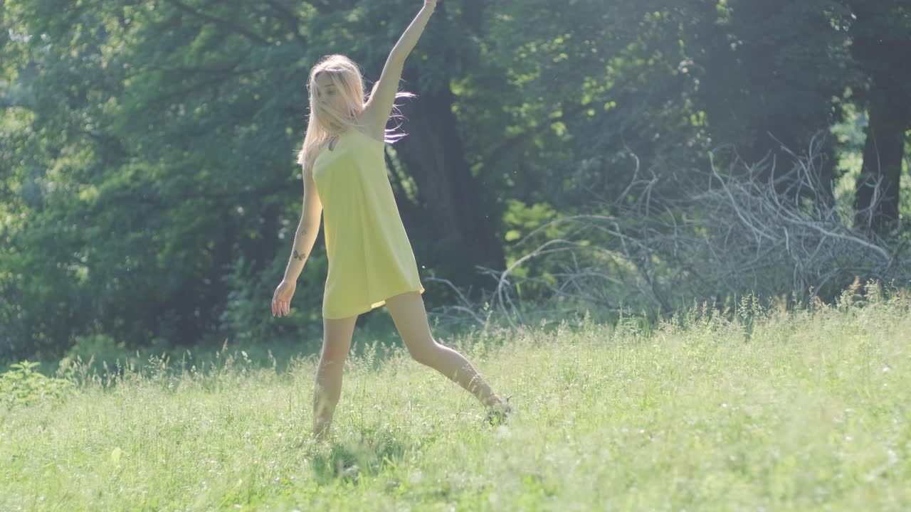 노란색 드레스를 입은 여자가 여름 공원에서 우아하게 춤을 춘다
