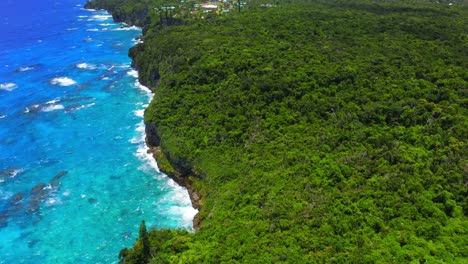 a drone captures a stunning aerial view of a tropical island coast featuring lush forests and a breathtaking blue lagoon