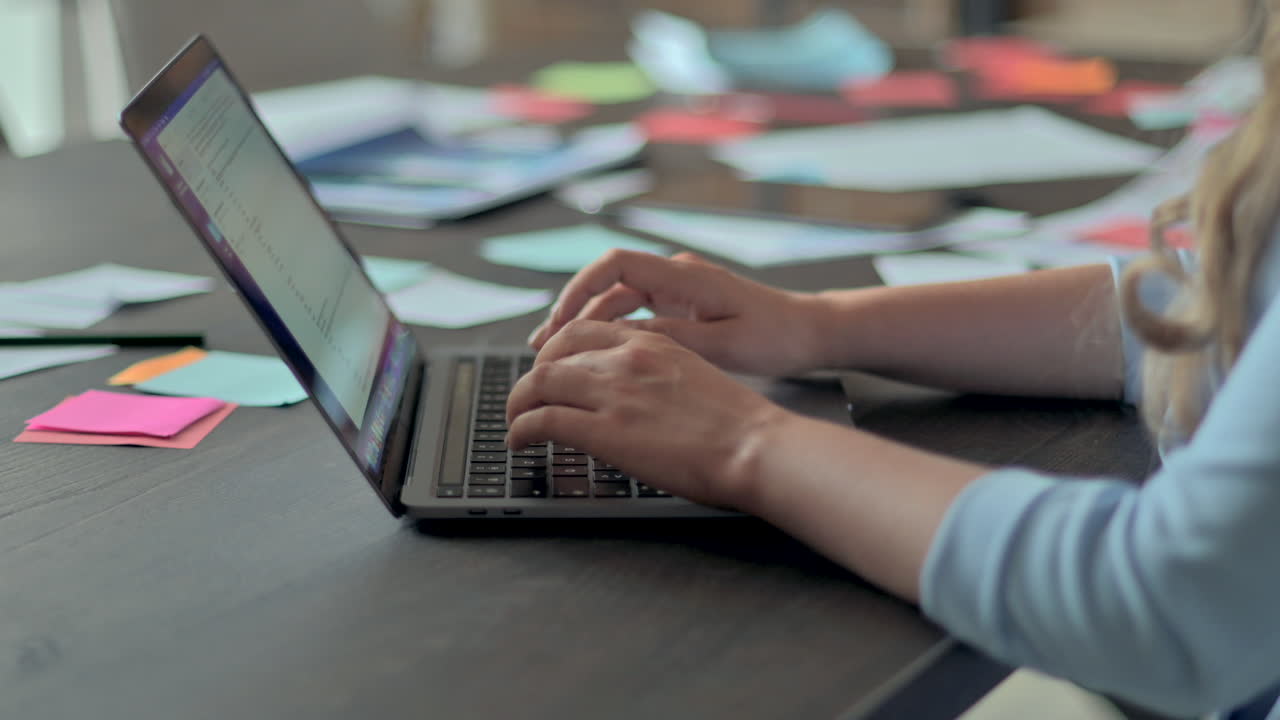 Woman in blue blazer typing on a laptop at a desk in an office