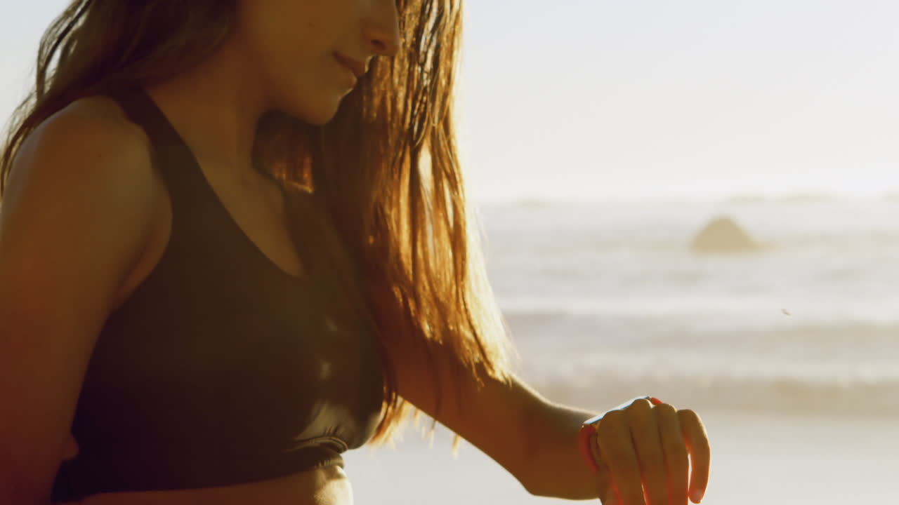 Donna in forma che usa lo smartwatch in spiaggia 4k