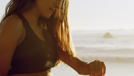 mujer en forma usando reloj inteligente en la playa 4k