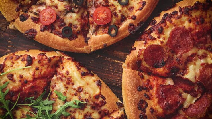 Vari tipi di pizza disposti su un tavolo di legno