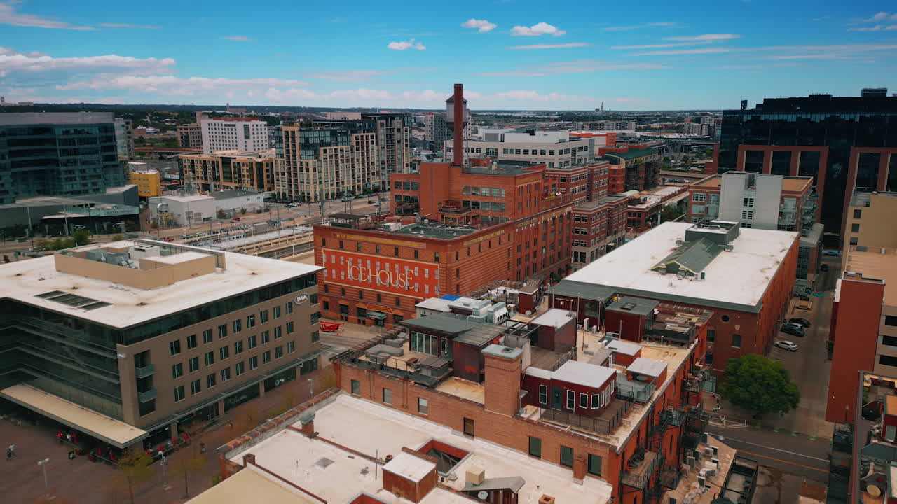 Denver, USA, 28 July 2025: Flying closer to the big red-brick building with a long pipe and a sign on the façade. Architecture of modern Denver, Colorado, United States