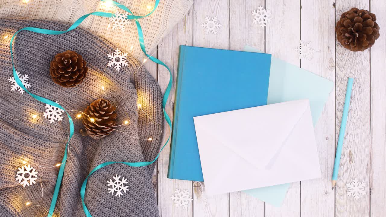 papel azul, libro y sobre para deseos de navidad y luces parpadeantes en ropa de punto.