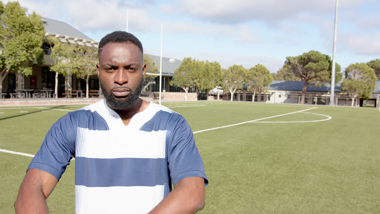 Standing on sports field, african american man crossing arms and looking determined, copy space
