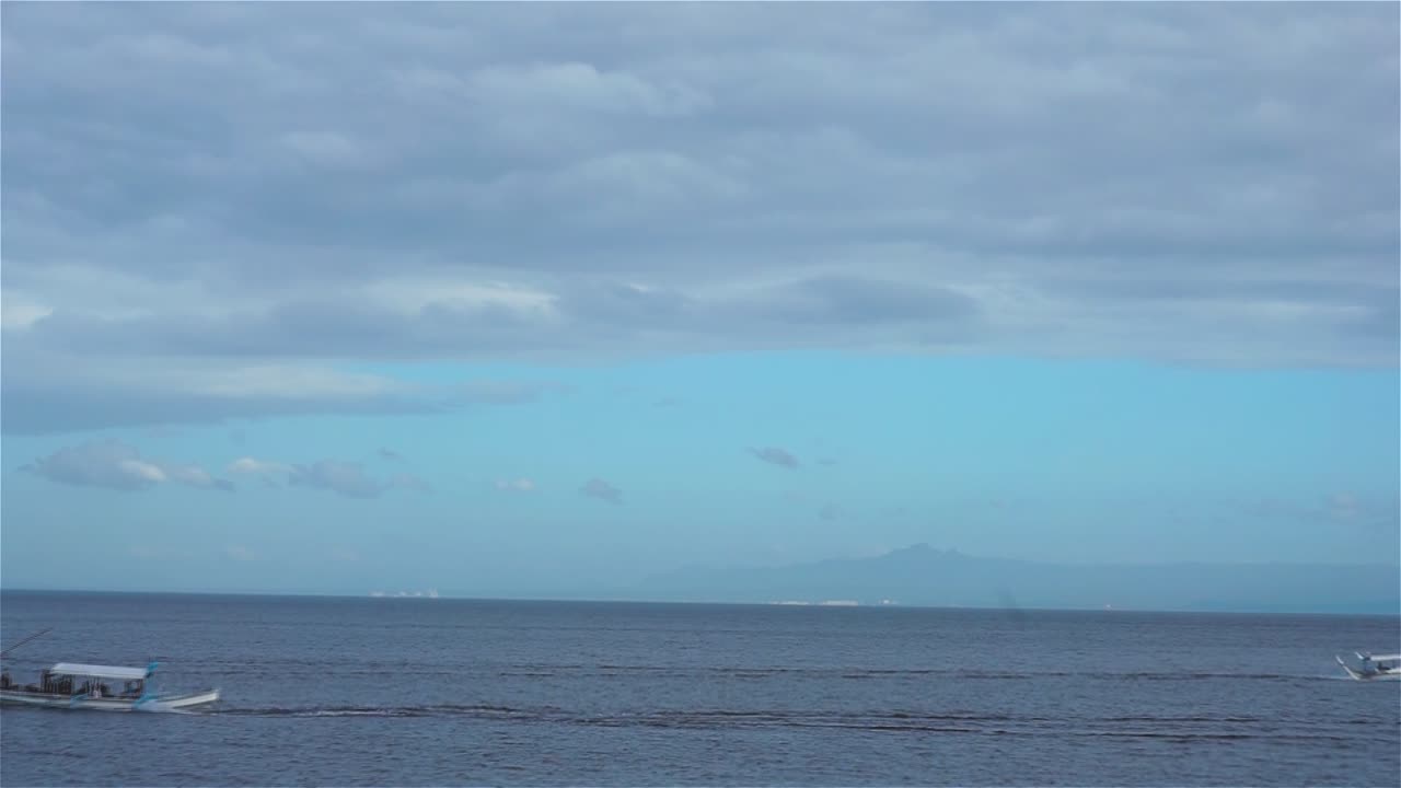 Two boats crossing their paths in a cloudy day.