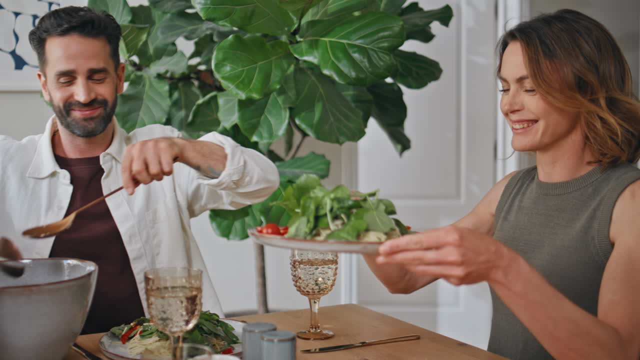 Bearded man putting salad communicating at table closeup. Parents child eating