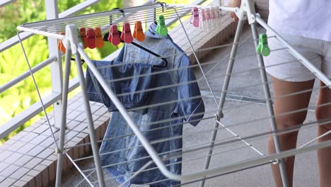 person hanging clothes on outdoor drying rack.