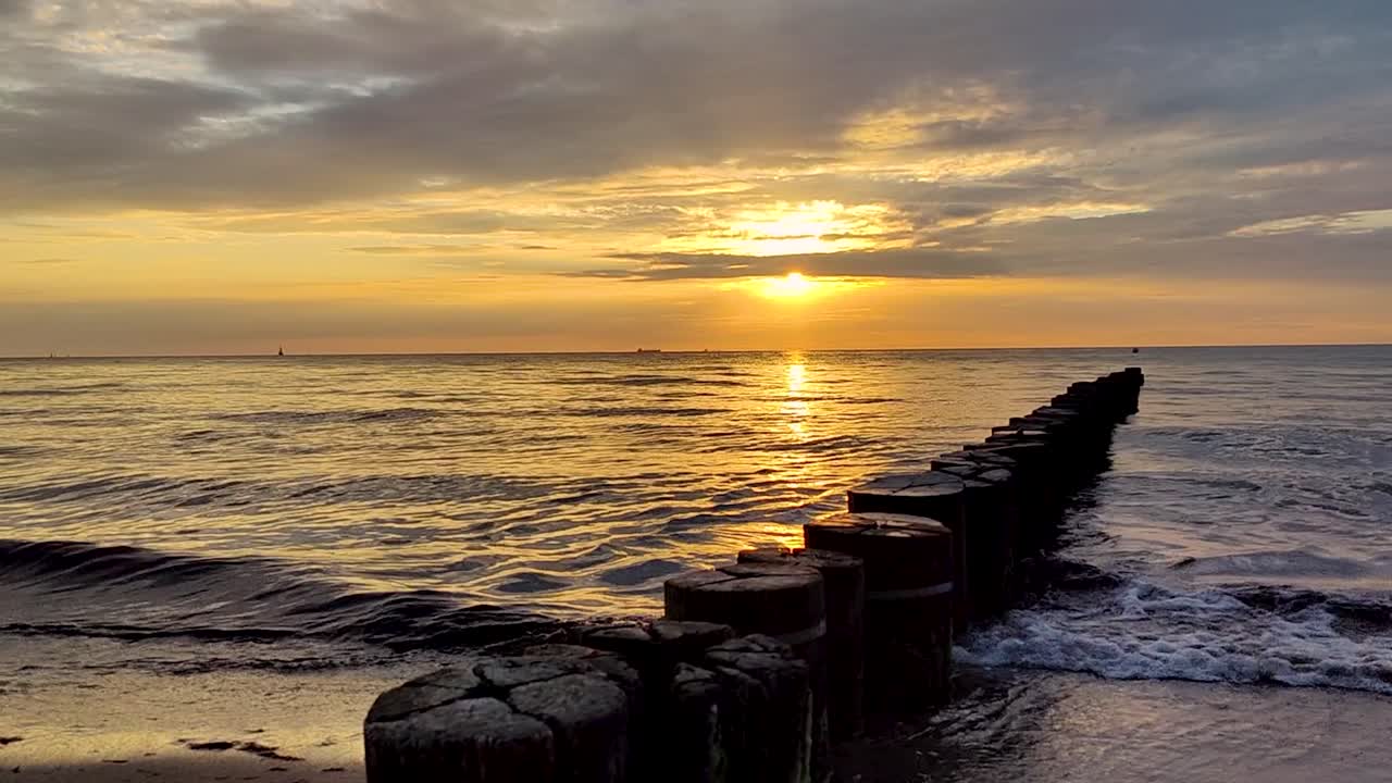 Primo piano di onde che si infrangono su una spiaggia del Mar Baltico al tramonto.