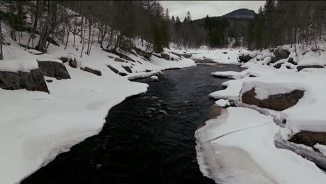 Antena-Escénica-Dron-Adelante-Revelar-Movimiento-Desierto-Canadiense-Mediados-De-Invierno-Cerca-Del-Norte-De-Quebec-Estación-De-Esquí-De-Stoneham-De-Congelado-Sobre-El-Río-Sautaurski-Río-Arriba