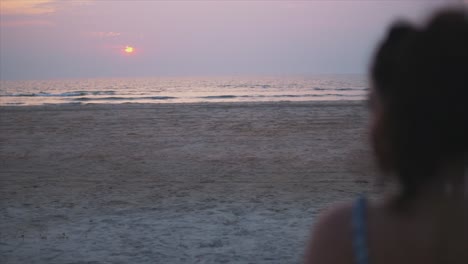mujer joven viendo la puesta de sol sobre el océano tranquilo
