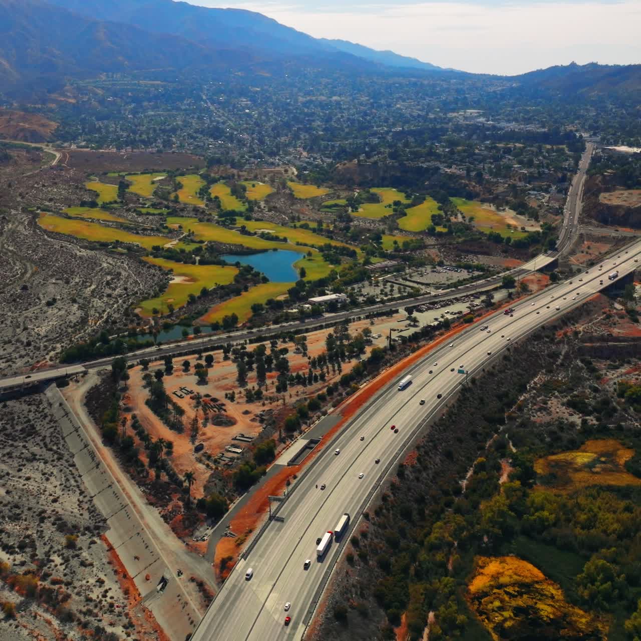 Unusual scenery of Los Angeles outskirts with highway going through. Mountains at backdrop. Aerial perspective