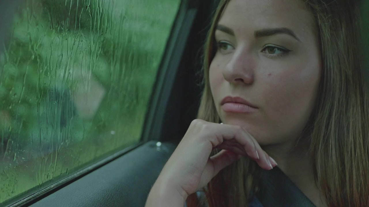A lady sitting in the passenger sit looking outside through a transparent window