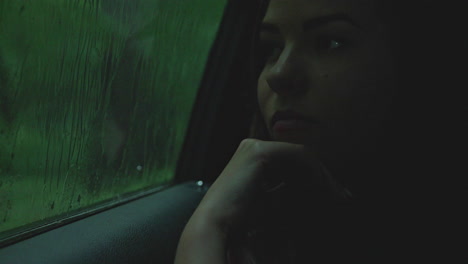 a lady sitting in the passenger sit looking outside through a transparent window