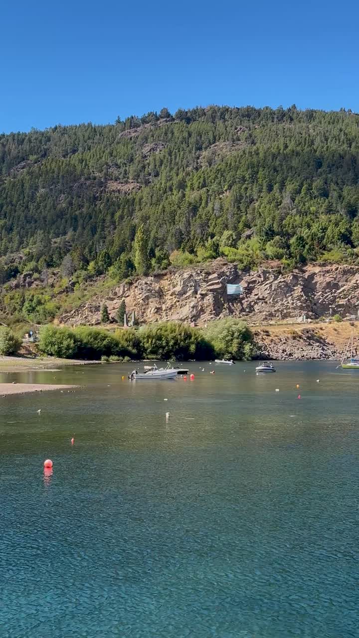 Clear blue water in San Martín de los Andes with a distant mountain, small boats in view